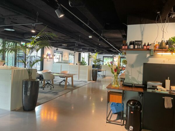 Moderne kantoorruimte aan de De Cuserstraat met open werkplekken, groene planten en een koffiehoek.
